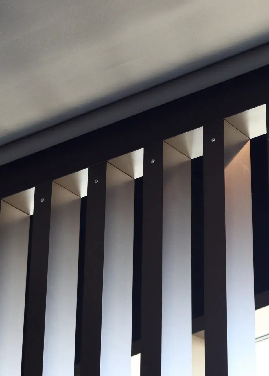 Verticale aluminium lamellenwand van LuxxOut onder een overkapping, voor een stijlvolle combinatie van privacy en zonfiltering.